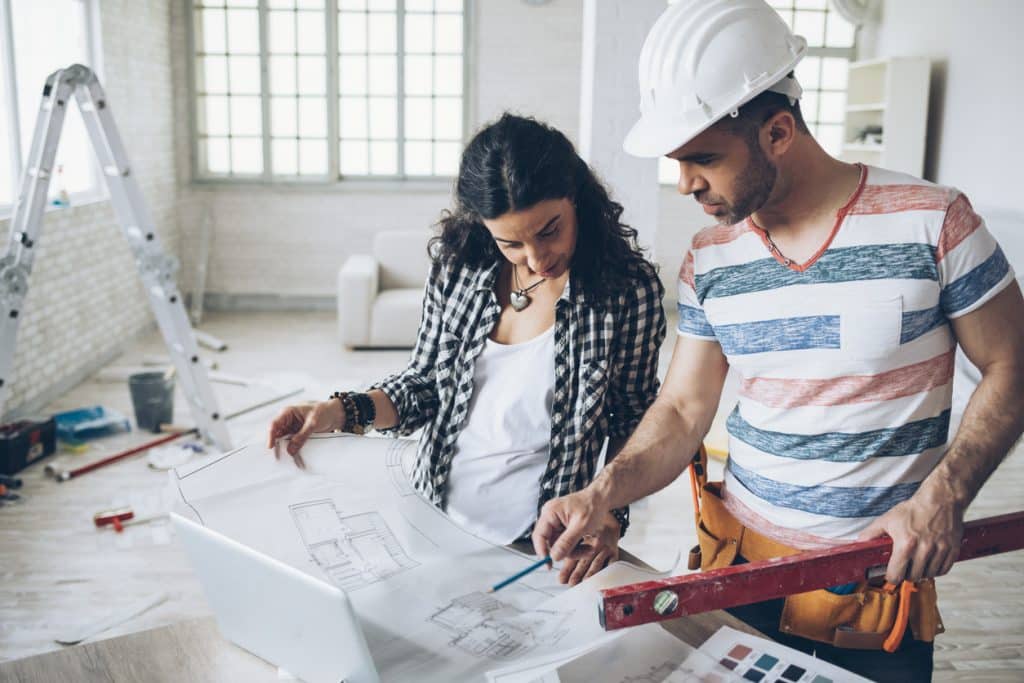 Young woman and construction worker looking at blueprints