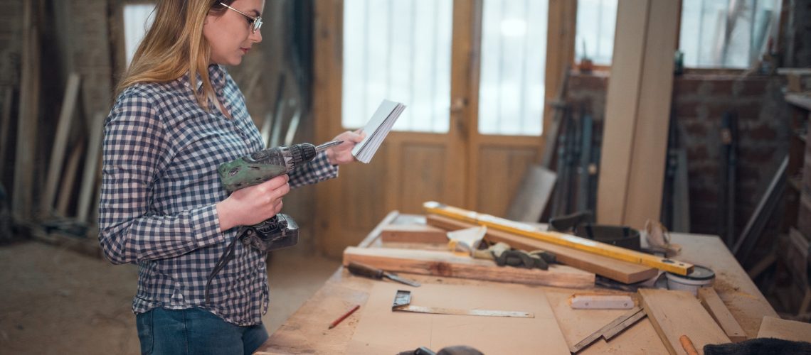 Young woman working in the workshop and making wooden objects